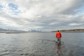 A man walking through knee deep water in a lake in Iceland.